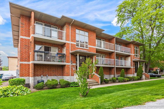 Front view of a brick multi-story building with balconies.
