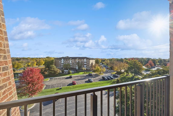 View of a residential building and surrounding area from a balcony with clear skies and sunlight.