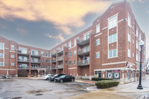Front view of a multi-story brick apartment building with balconies.