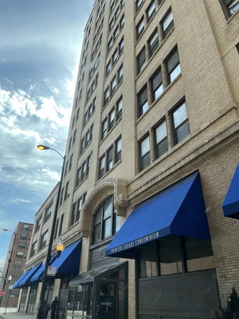 Front view of a multi-story condominium building with blue awnings.