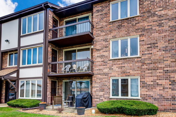 Front view of a three-story brick apartment building with balconies.