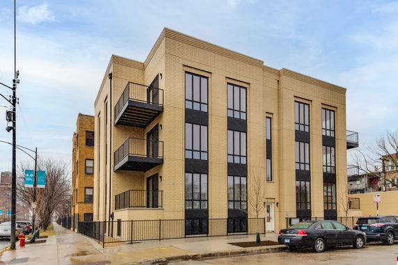 Front view of a modern multi-story building with brick facade and balconies.