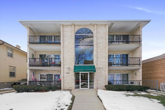 Front view of a three-story apartment building with balconies and an entrance canopy.