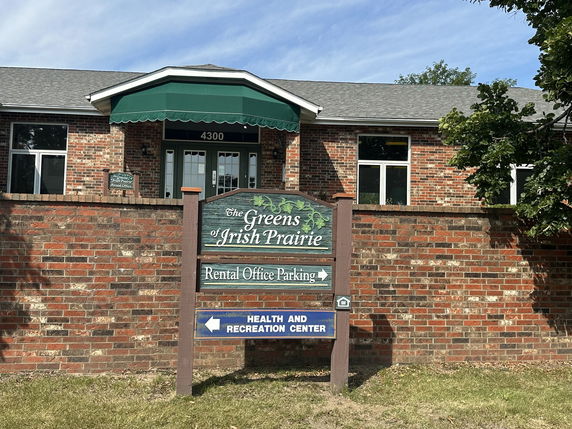 Front view of a brick building with a green awning and a sign for a rental office.