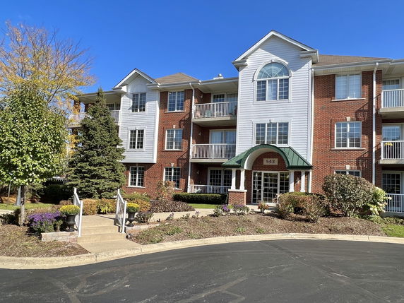 Front view of a three-story building with a brick facade and balconies.