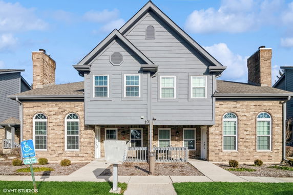 Front view of a two-story house with a brick and gray panel exterior.
