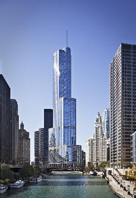 Front view of a tall skyscraper surrounded by other buildings.