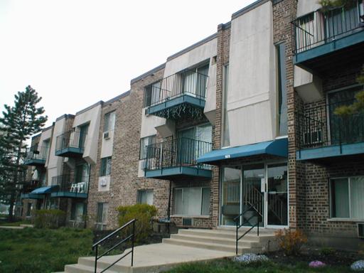 Front view of an apartment building with brick facade and multiple balconies.