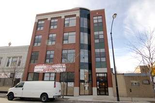 Front view of a multi-story brick building with large windows.