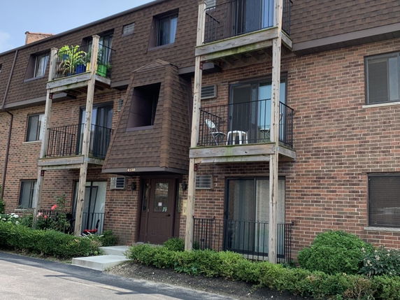 Front view of a brick apartment building with balconies.