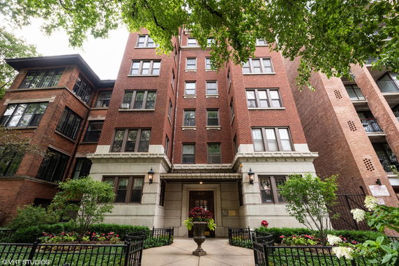 Front view of a multi-story brick apartment building with numerous windows.
