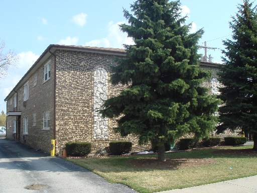 Front view of a two-story brick building with large trees nearby.