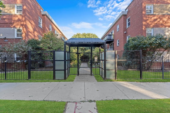 Front view of a multi-story brick residential building with gated entrance.