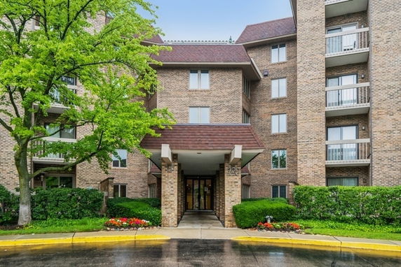 Front view of a multi-story brick apartment building with a covered entrance.