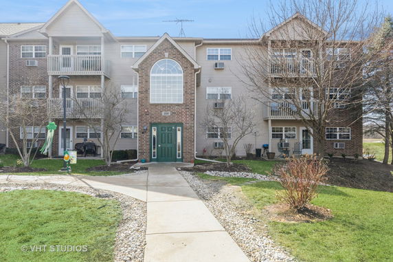 Front view of a three-story residential building with balconies and a central entrance.