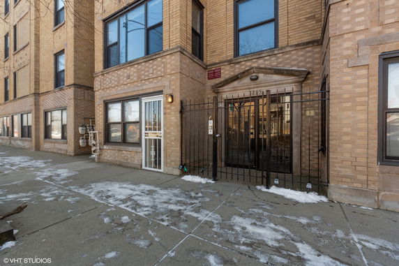 Front view of a multi-story brick building with gated entrance.