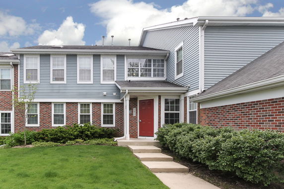 Front view of a two-story house with a red door and multiple windows.