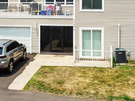 Front view of a house with a garage and outdoor air conditioning unit.