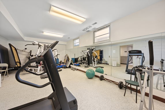 Gym area with various exercise equipment and mirrors.