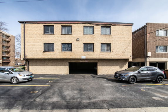 Front view of a three-story brick building with parking area.