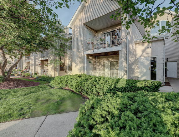 Front view of a multi-story residential building with balconies and landscaped garden.
