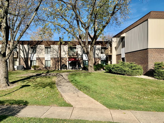 Front view of a two-story apartment building with brick and paneling exterior.