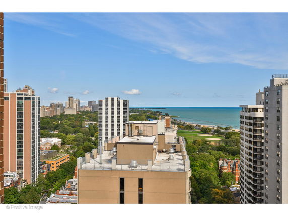 Panoramic view of a cityscape with tall buildings and a distant view of a body of water.