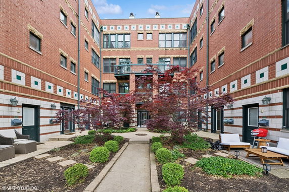 Front view of a multi-story brick building with windows and a walkway leading to the entrance.