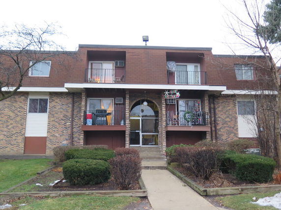 Front view of a two-story brick apartment building with balconies.