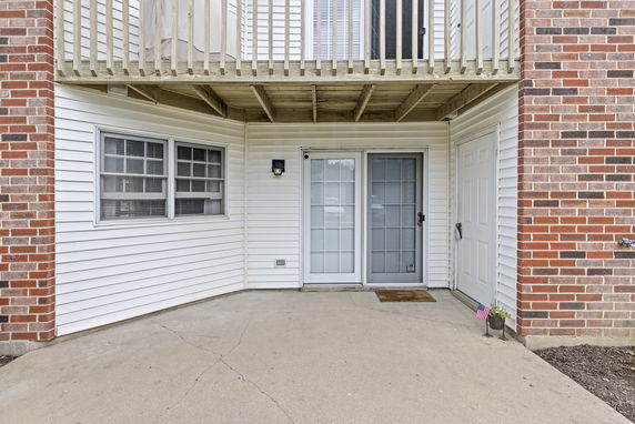 Front view of a building with a patio and door, brick and siding exterior.