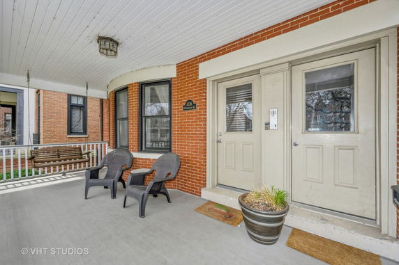 Front view of a house with a porch, brick exterior, and two doors.