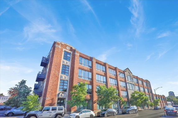 Front view of a multi-story brick building with large windows.