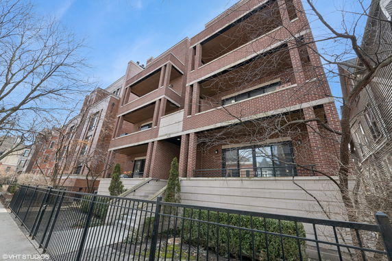 Front view of a multi-story brick apartment building with balconies.