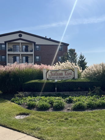 Front view of a three-story brick apartment building with balconies and a sign reading 'Chatham East'.