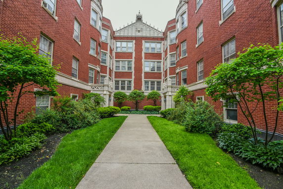 Front view of a large brick apartment building with multiple windows and decorative stonework.