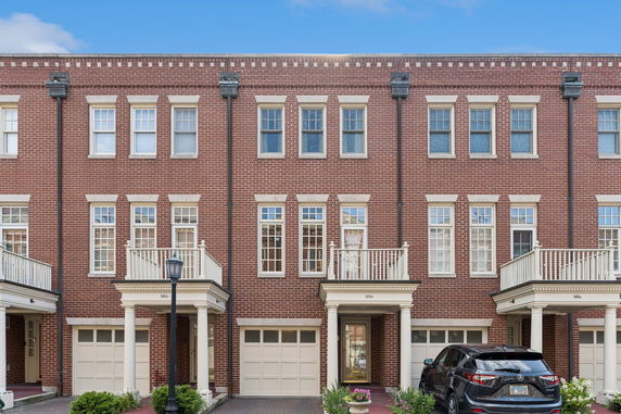 Front view of a multi-story brick townhouse with a garage and balcony.
