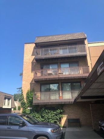 Front view of a multi-story building with balconies and a covered parking area.