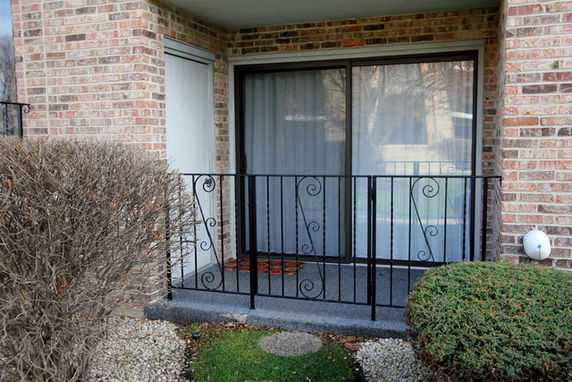 Front view of a building with a small balcony and sliding glass door.