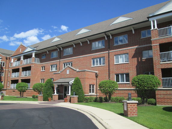 Front view of a multi-story brick apartment building with balconies.