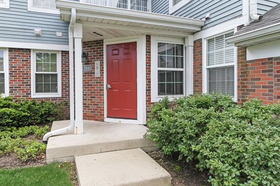 Front entrance of a building with a red door and brick facade.