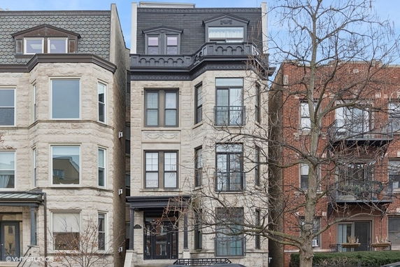 Front view of a multi-story residential building with a stone facade and mansard roof.