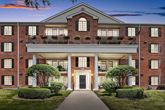 Front view of a multi-story brick building with columns and a balcony.