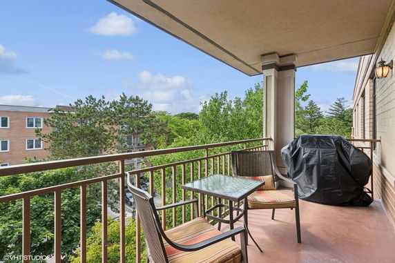 Balcony view showing outdoor furniture and nearby buildings with trees.