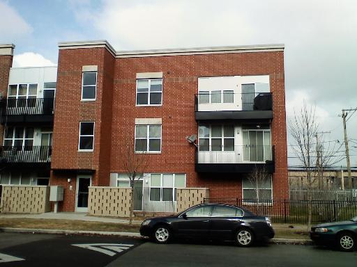 Front view of a three-story brick building with balconies.