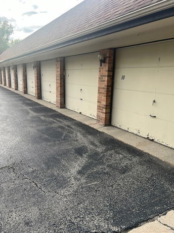 Row of covered parking garages with brick columns and numbered doors.