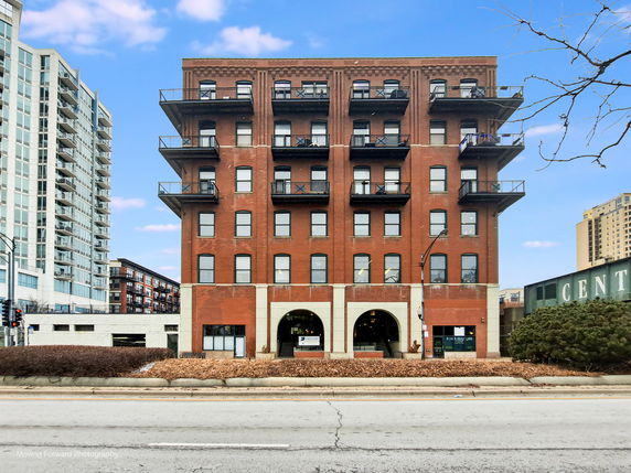 Front view of a multi-story brick building with balconies.