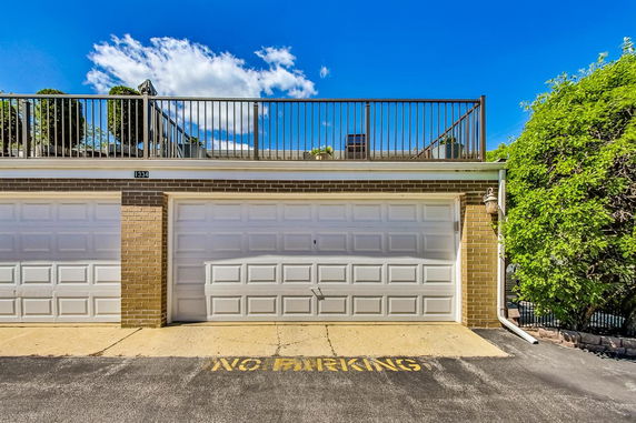 Front view of a building with two garage doors and a rooftop terrace.