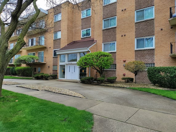 Front view of a multi-story brick apartment building with balconies.