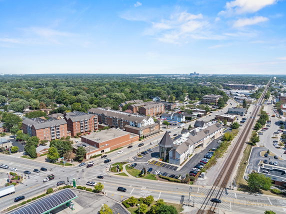 Aerial view of a suburban area with multiple residential and commercial buildings along a railway line.