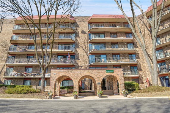 Front view of a multi-story brick apartment building with multiple balconies.